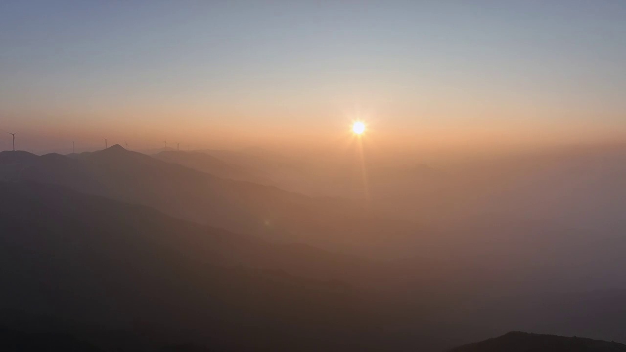 夕阳暮色中高海拔山顶的风力发电风车和山谷中涌动的云雾视频素材