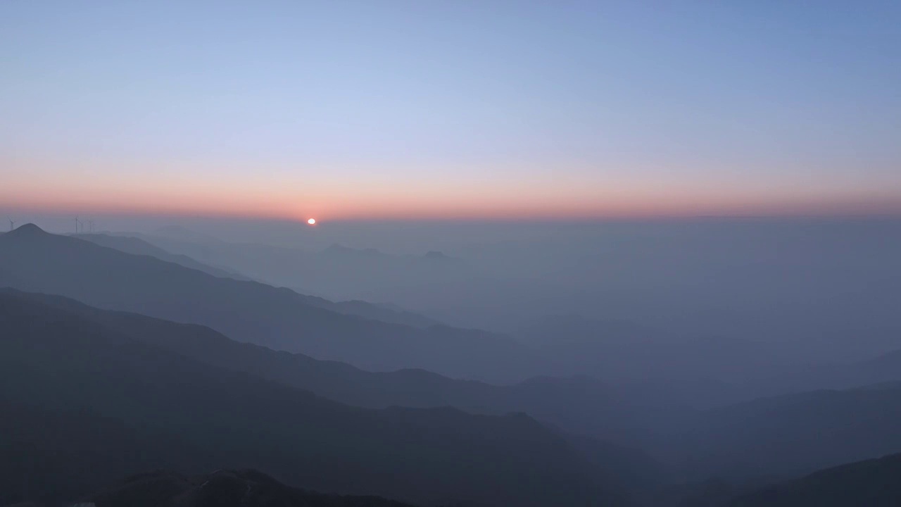 夕阳暮色中高海拔山顶的风力发电风车和山谷中涌动的云雾视频素材