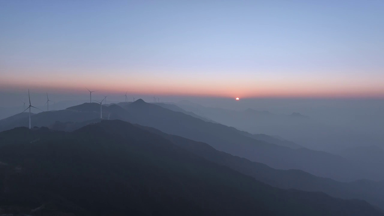 夕阳暮色中高海拔山顶的风力发电风车和山谷中涌动的云雾视频素材