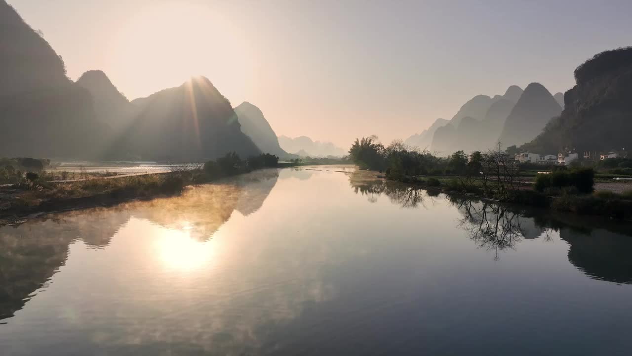 清晨阳朔遇龙河上的薄雾和日出形成的丁达尔现象视频素材