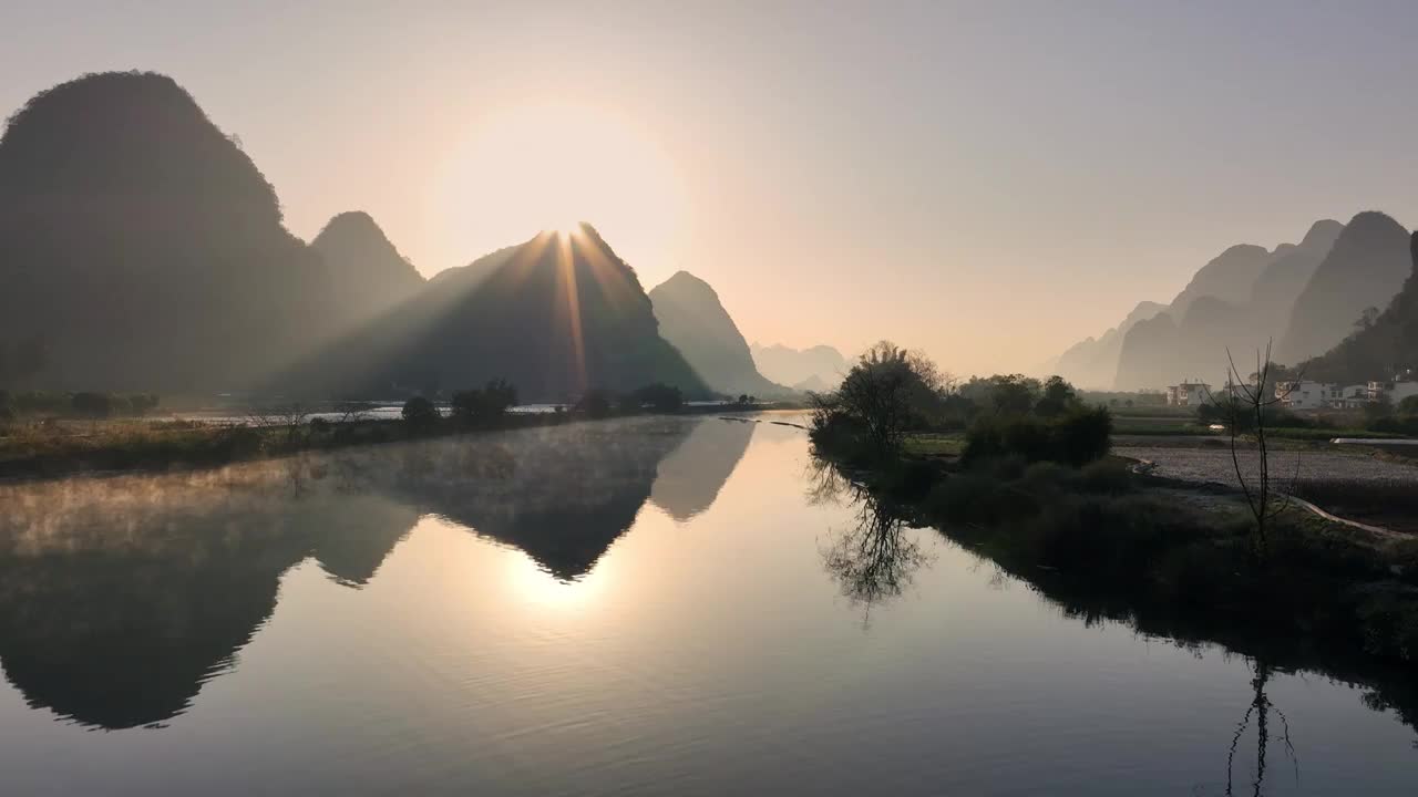 清晨阳朔遇龙河上的薄雾和日出形成的丁达尔现象视频素材