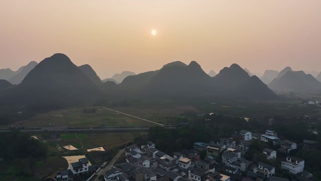 傍晚落日余晖下穿过山间田园的高速公路视频素材