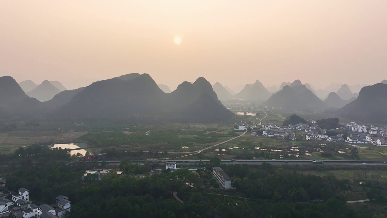 傍晚落日余晖下穿过山间田园的高速公路视频素材