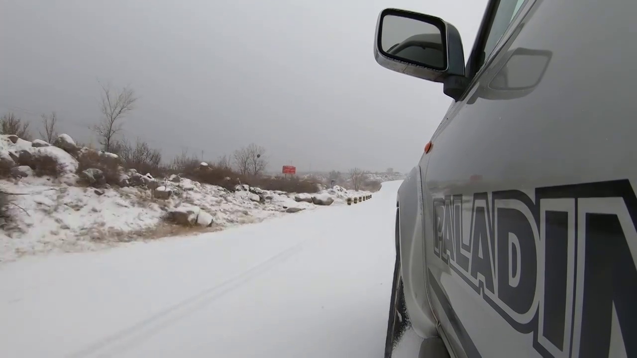 车辆行驶在正在下雪的山边公路上左侧视角视频素材