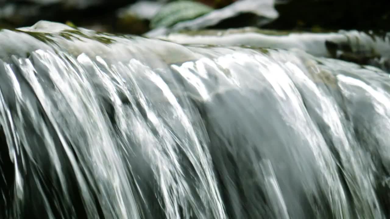 春天气息渐渐回暖大地形成了清澈的溪水沿山涧缓缓流淌发出潺潺声音冲刷着岩石初春溪水湍急形成了泉水瀑布视频素材