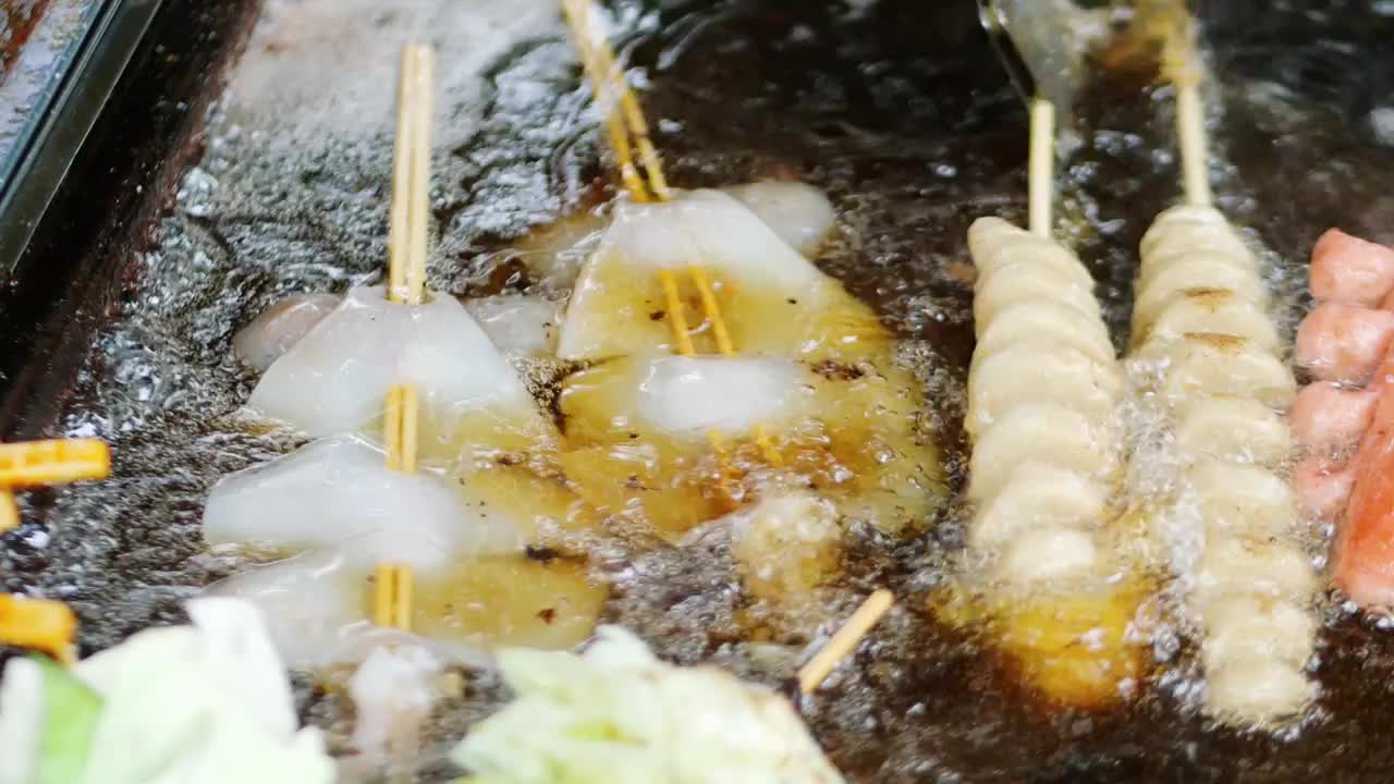 街边乡村小吃店铁板油炸美味食品油泼鲜鱿鱼香肠面筋包菜豆腐开花肠热狗滚油炸制美食街夜市小摊市井气息烟火视频素材