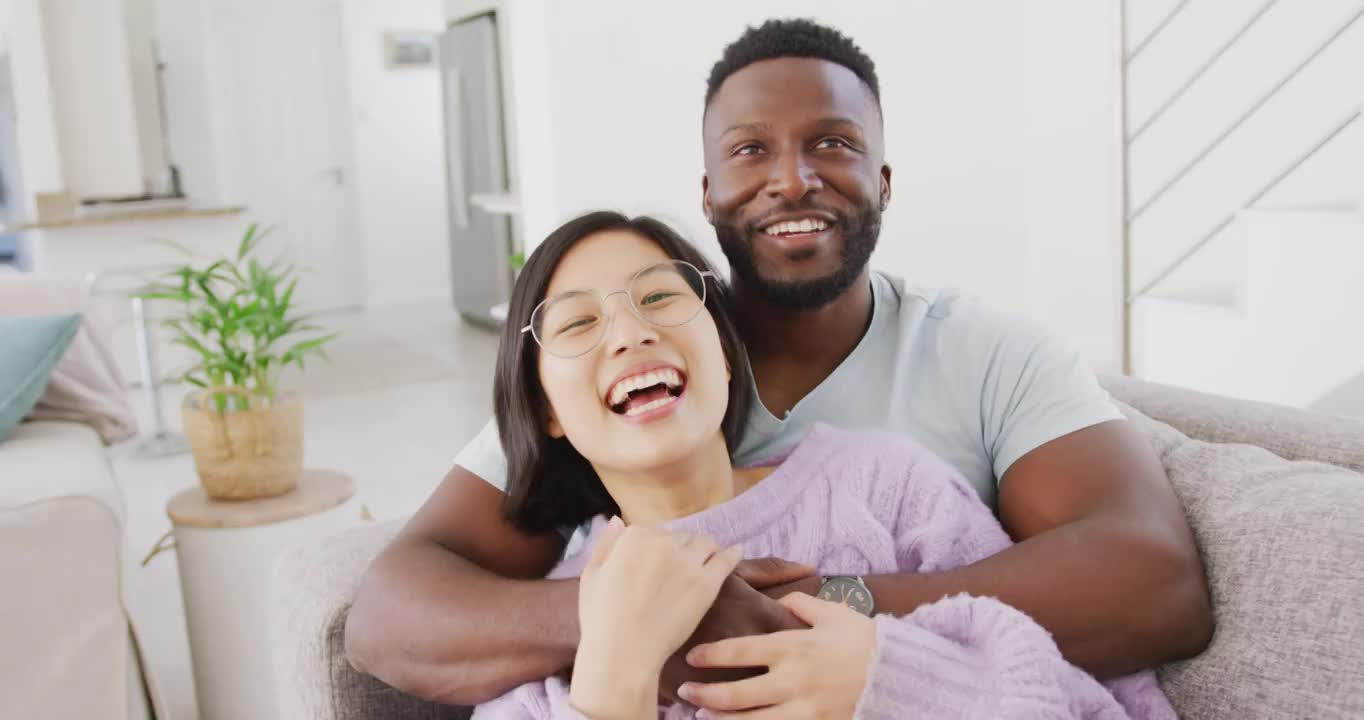 Portrait of happy diverse couple embracing in living room视频素材