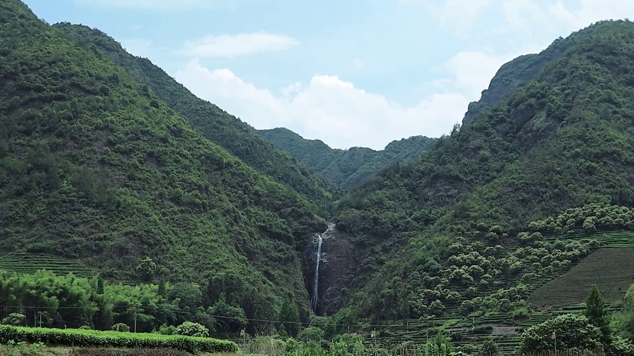 蓝天白云下两山之间的一线瀑布视频素材