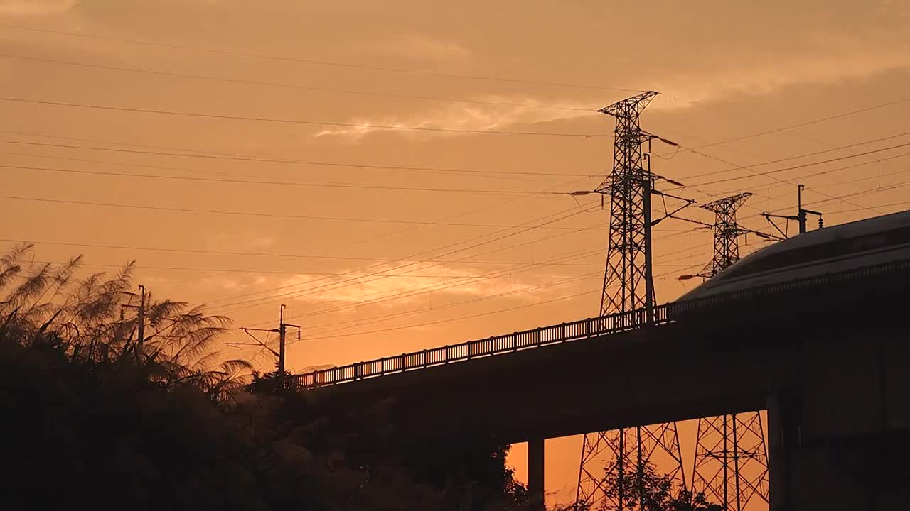 夕阳下行驶在电网铁塔下的高铁动车视频素材