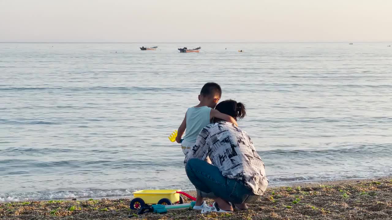 小男孩搂着妈妈的脖子在大连傅家庄海边视频下载