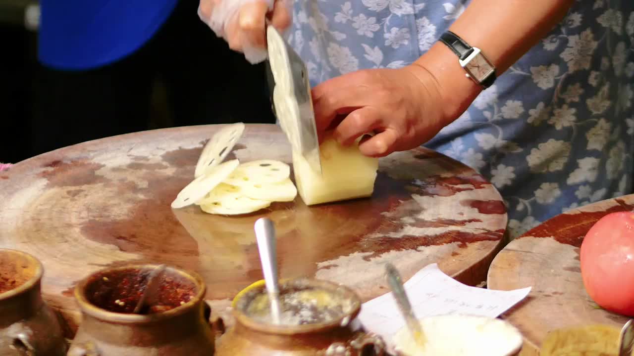 餐厅饭馆厨房的厨师正在熟练切开莲藕以便与炒制调味菜色一根莲藕在案板上被厨师手起刀落快速切片成薄片视频素材