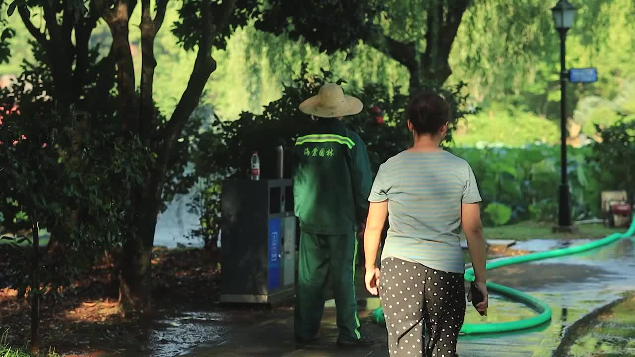 公园里工人正在炎热夏日给植物浇水视频素材