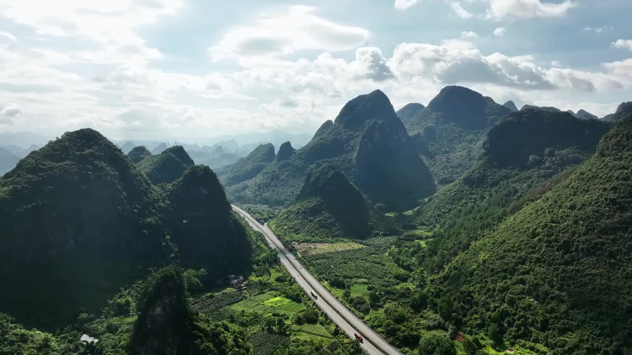 蓝天白云下穿过喀斯特地貌山峰田园的高速公路视频素材