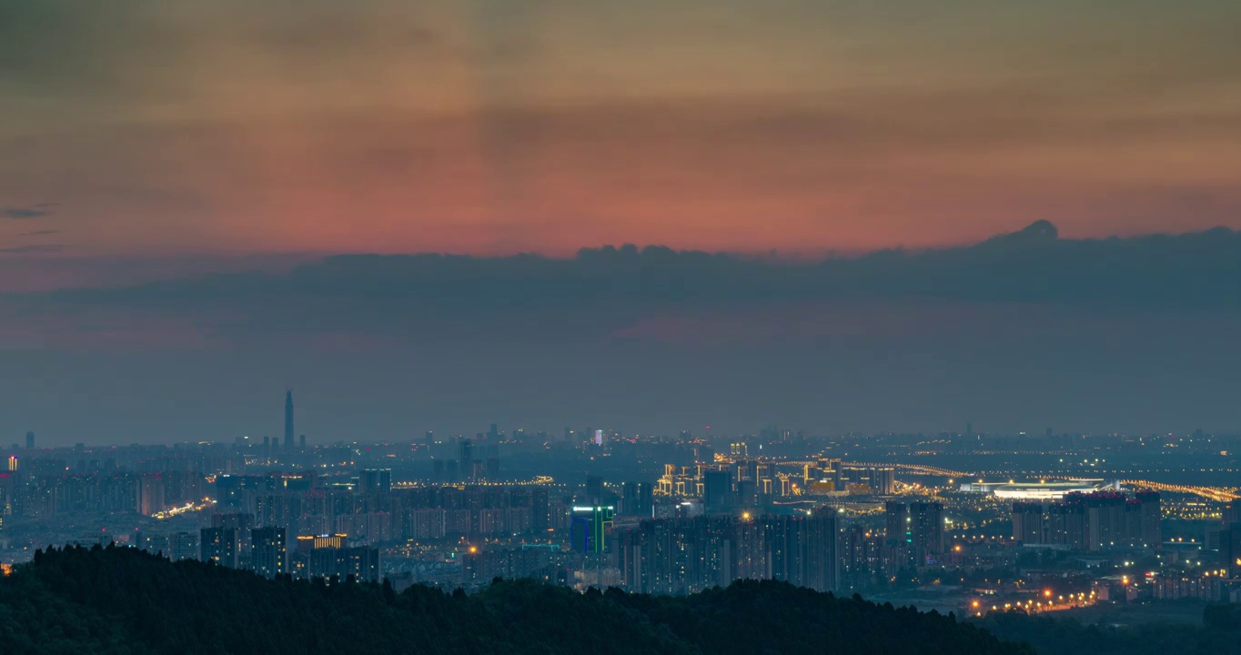 龙泉山上俯瞰雾蒙蒙的成都市区，夕阳西下，日转夜。大运会主体育馆亮起明亮的灯光视频素材