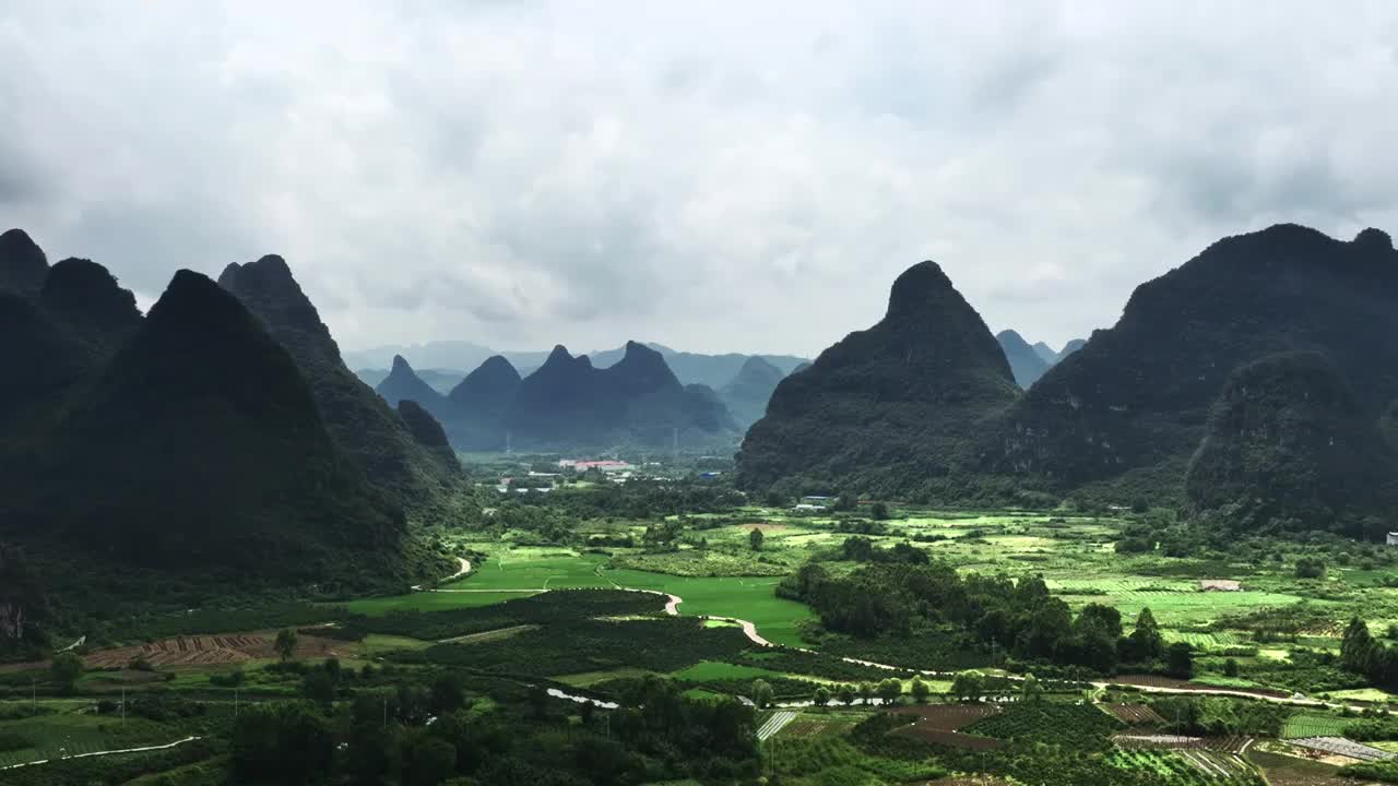 航拍桂林秋天多云天气下喀斯特山峰间的村庄和稻田视频素材