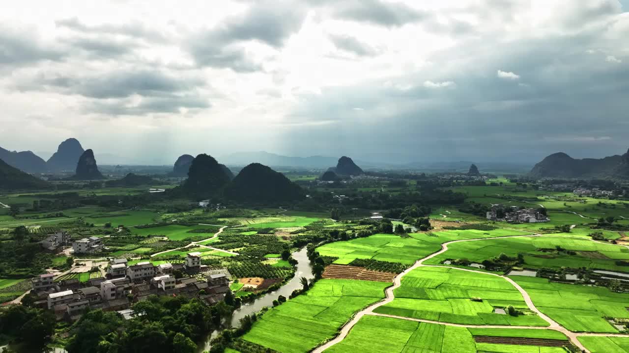 蓝天白云下航拍桂林喀斯特地貌山峰间的村庄和绿色稻田视频素材