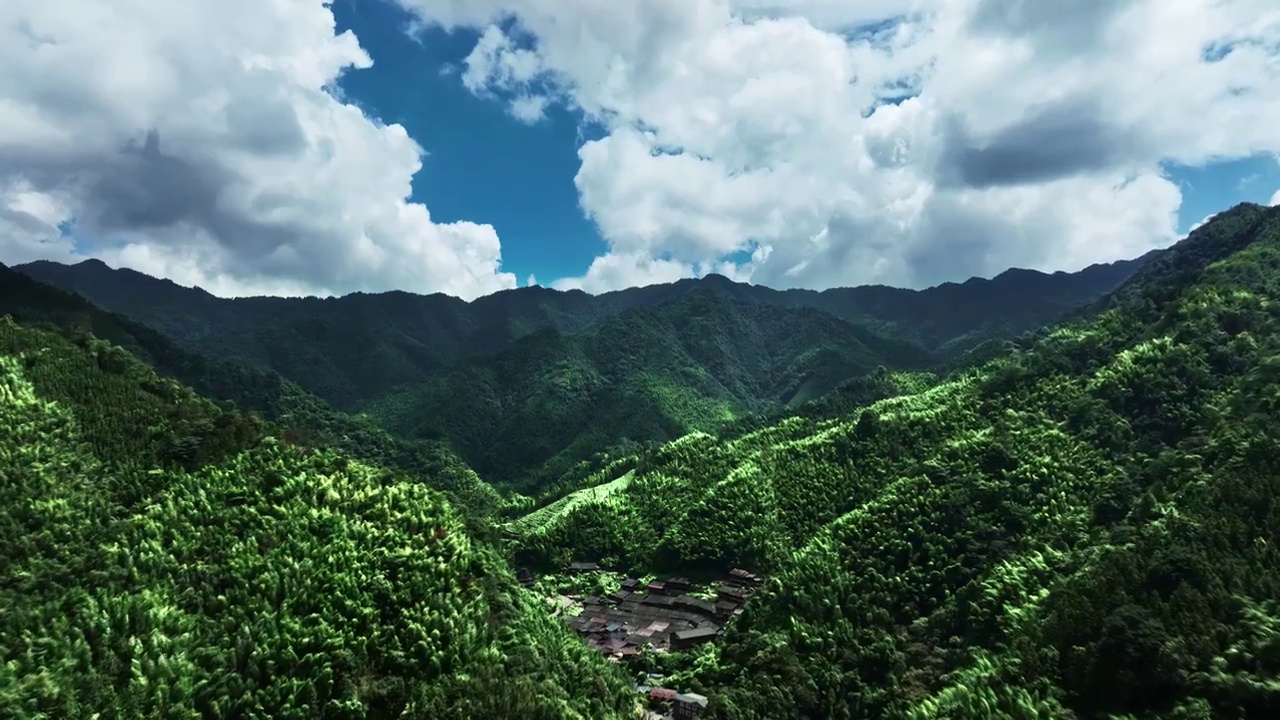 航拍蓝天白云阳光下桂林山区绿色的山脉和山谷中的少数民族村寨视频素材