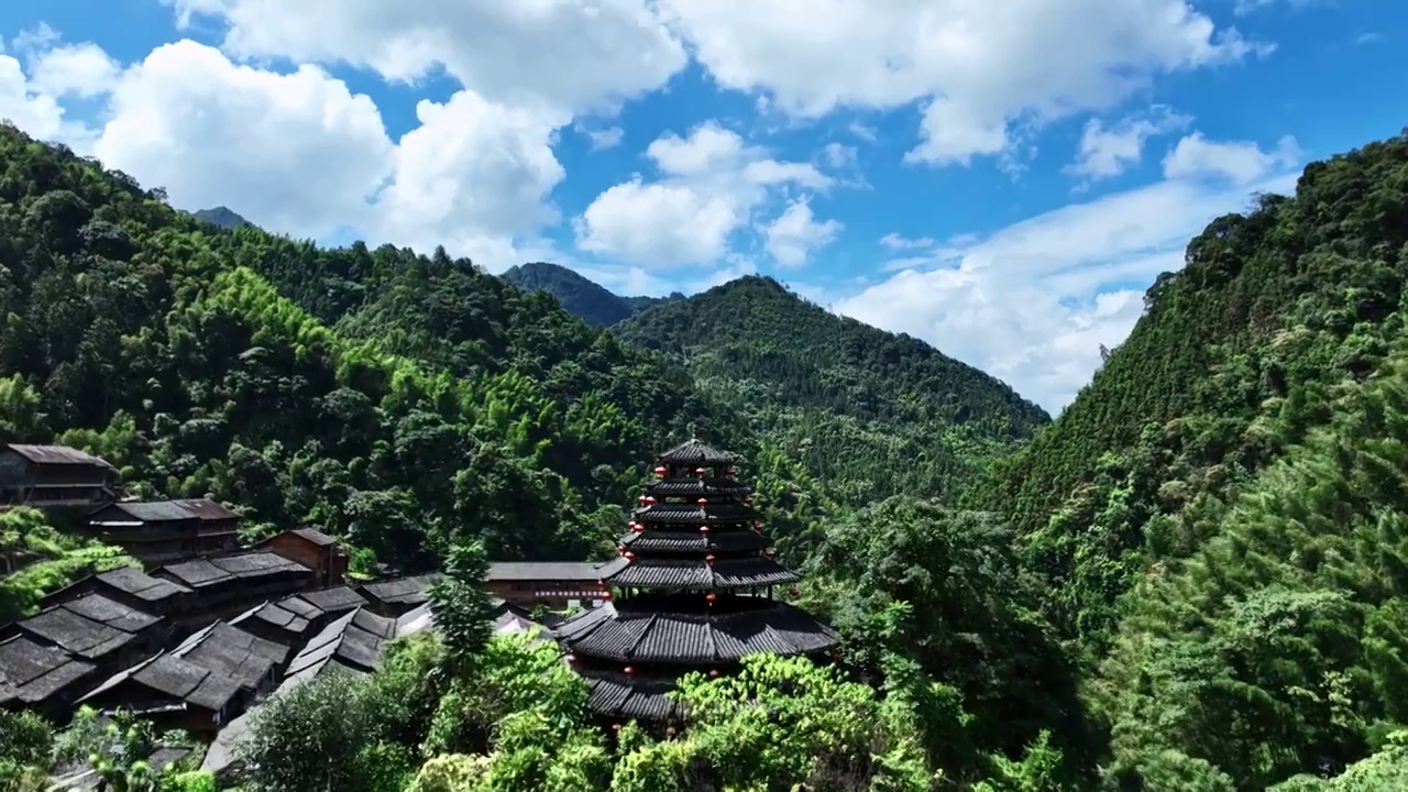 航拍蓝天白云阳光下桂林山谷中的瑶族村寨和鼓楼视频素材