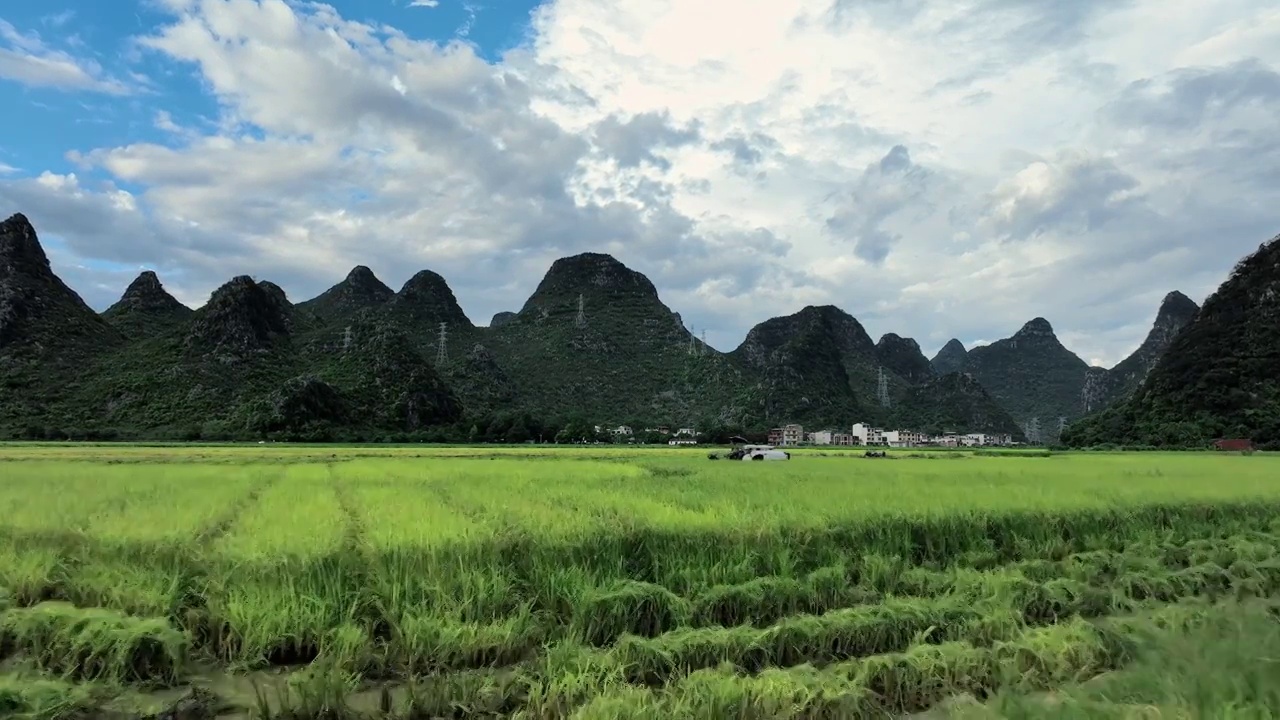 秋天阳光下桂林山峰间稻田里的收割机正在作业视频素材