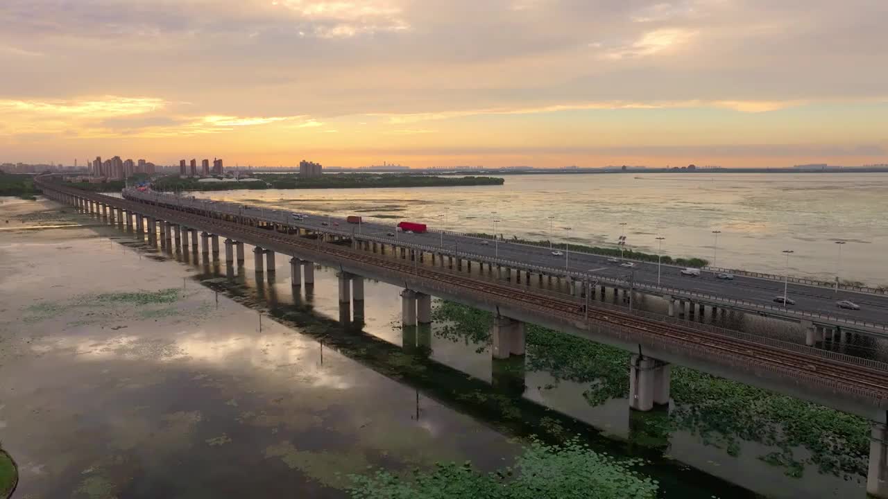 傍晚时分晚霞里的苏州阳澄湖上高铁与车流风景航拍视频素材