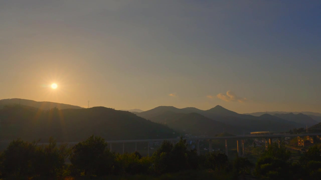 晴朗天空下午夕阳西下太阳落山晚霞彩云山峰延时视频素材