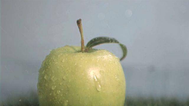 水滴落在青苹果上慢镜头，在灰色背景下视频素材