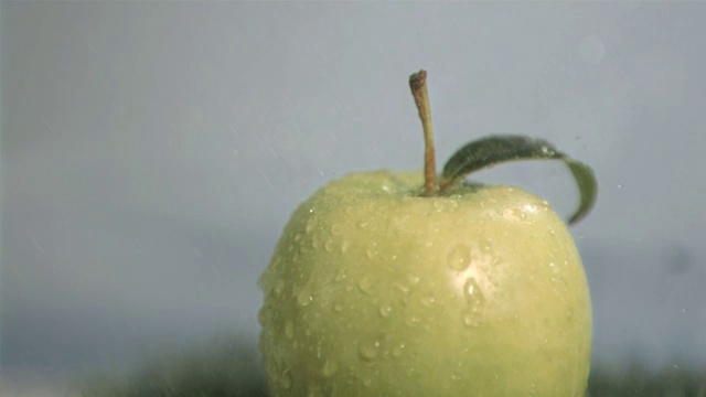 水滴落在青苹果上慢镜头，在灰色背景下视频素材