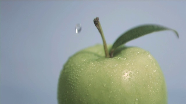 一滴水落在青苹果上，在灰色背景下视频素材