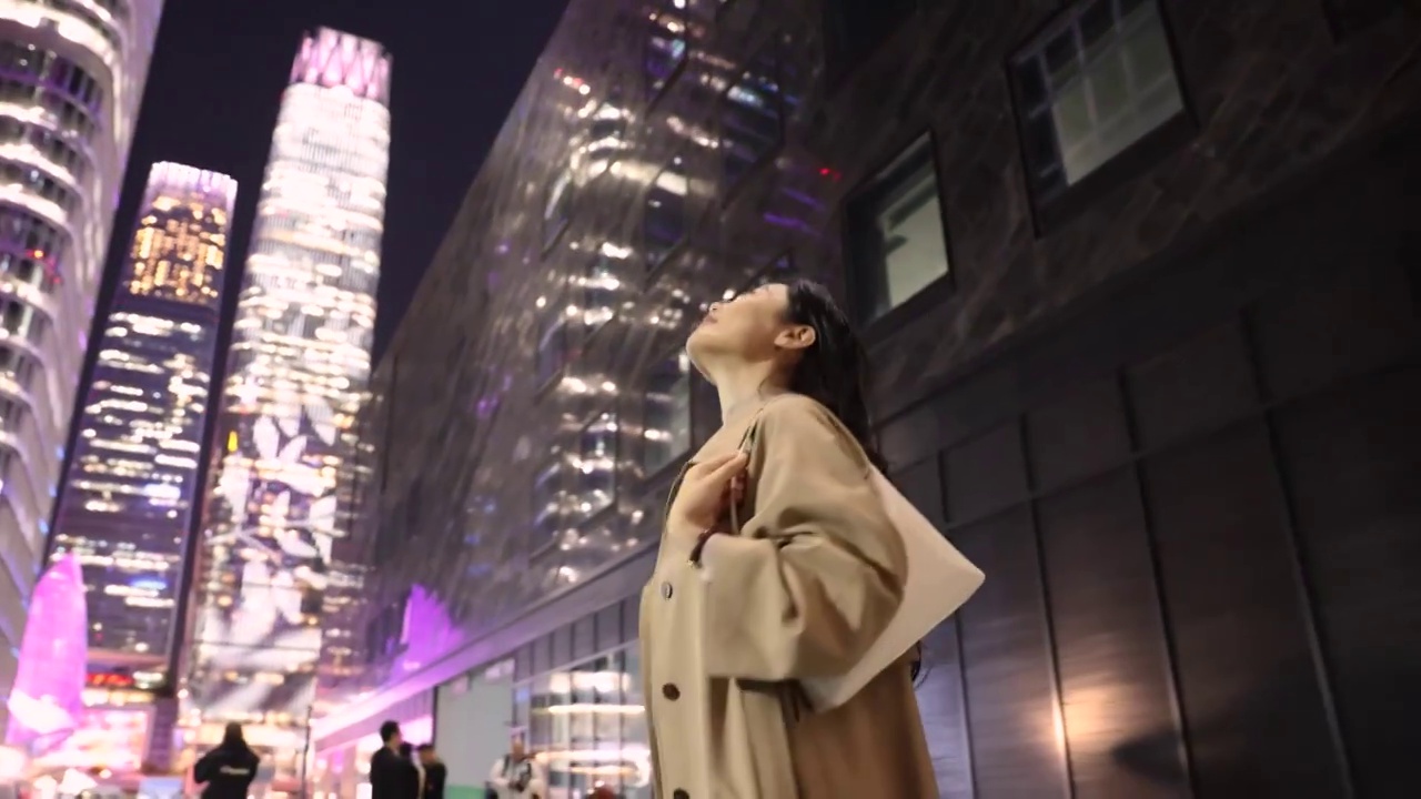 夜晚高知商务女子在城市街道上仰头欣赏城市夜景视频素材