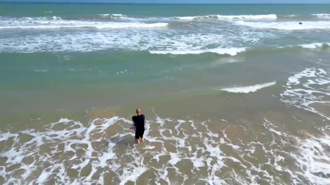 航拍海南琼海人像：爷爷和孙子在博鳌海岸线沙滩嬉戏冲浪视频素材