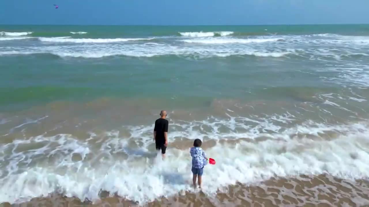 航拍海南琼海人像：爷爷和孙子在博鳌海岸线沙滩嬉戏冲浪视频素材