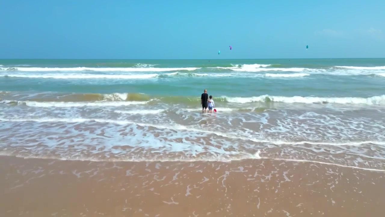 航拍海南琼海人像：爷爷和孙子在博鳌海岸线沙滩嬉戏冲浪视频素材