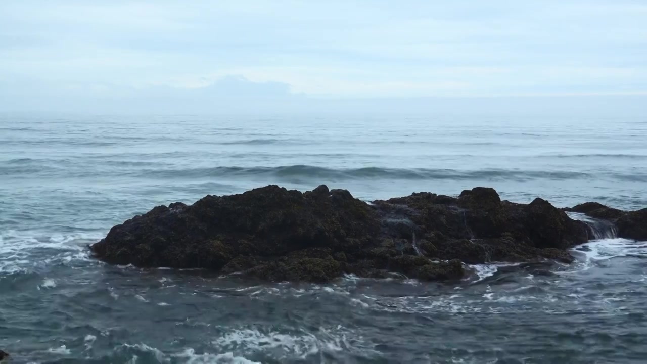 海岩石与移动的波浪在背景多云的地平线。夹。岩石的岩石视频素材