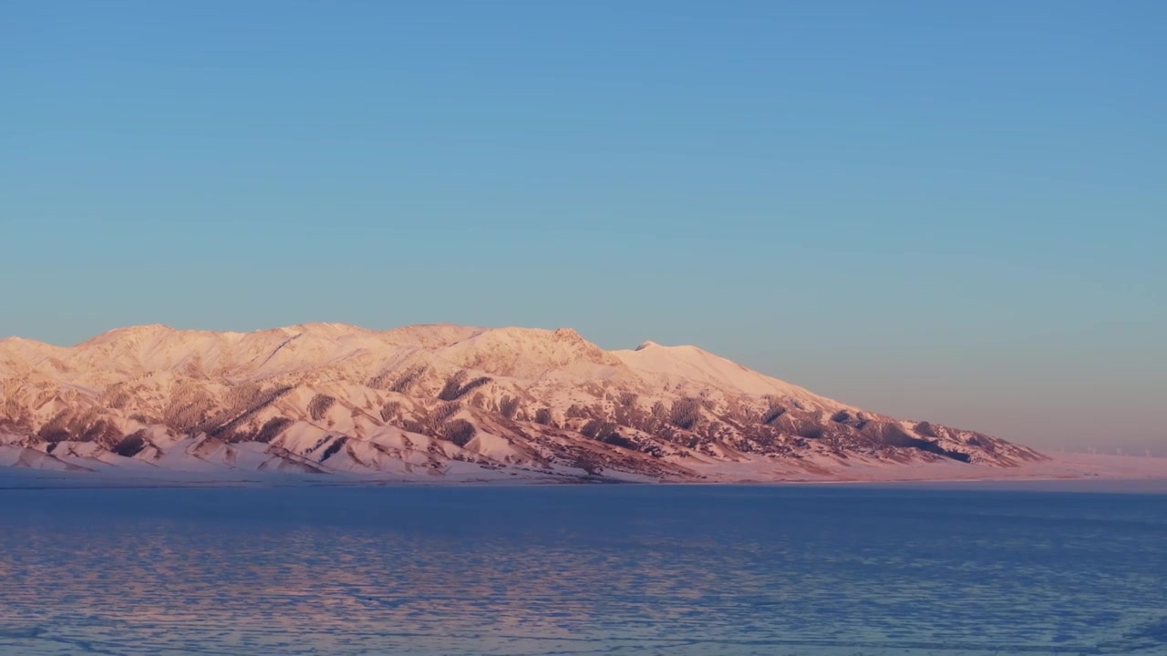 航拍冬季新疆赛里木湖雪山冰湖蓝冰日照金山夕阳雪山纹理视频下载