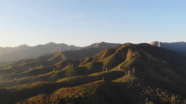 日落黄昏时山体和旋转的风轮机被阳光照亮视频素材