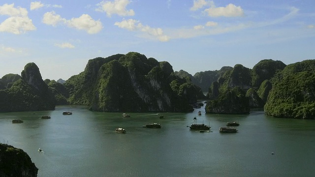 当云朵从越南广宁省下龙湾上空飞过时，船在下龙湾壮观的石灰岩喀斯特系统中四处航行，争夺位置。视频素材