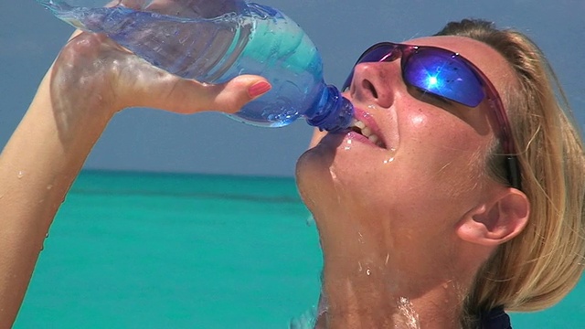 口渴的女人在海滩上喝水视频素材