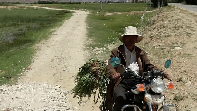 在西藏拉萨山区的土路上骑摩托车的男子视频下载