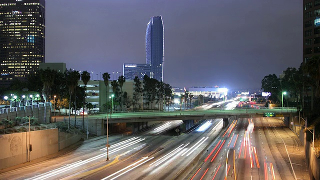 夜间高速公路上的交通和灯火通明的摩天大楼/美国加州洛杉矶视频素材