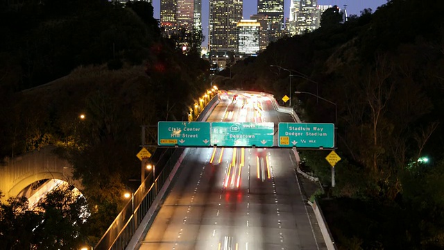 T/L WS TU照亮市中心的摩天大楼与高速公路上的交通前景，黄昏/美国加州洛杉矶视频素材