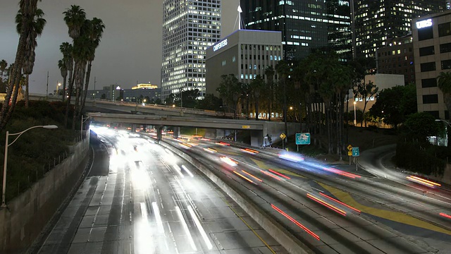 夜间高速公路上的交通和灯火通明的摩天大楼/美国加州洛杉矶视频素材