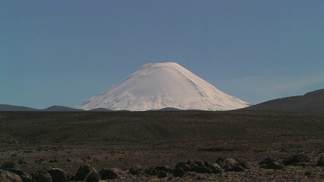 雪覆盖了帕里纳科塔火山后面的一些贫瘠的棕色山丘和蓝天/塔拉帕卡，智利视频素材