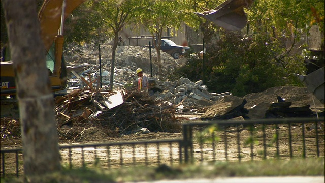 建筑工人正在清理建筑工地的瓦砾，将其放入铲斗中视频素材