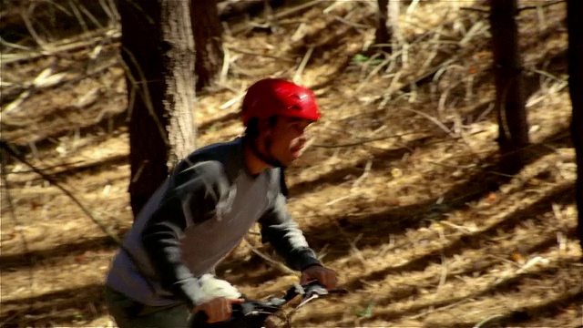 侧视图男子骑山地车上山在树林视频素材