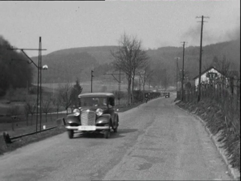 1935年B/W蒙太奇汽车沿着乡村公路行驶，火车靠近公路，两个人骑着自行车/黑福雷斯特，德国视频素材