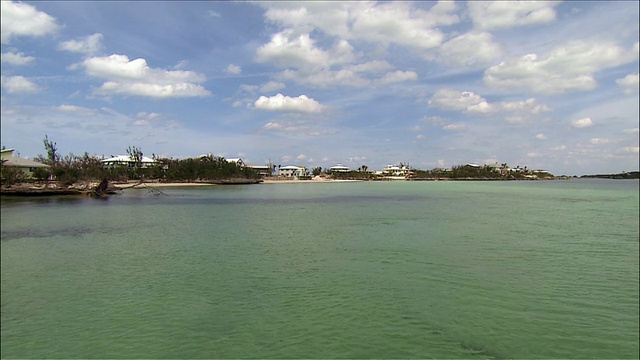 宽阔的镜头，在海滩海湾广阔的水域与度假村的背景/平移到海上的船只视频素材