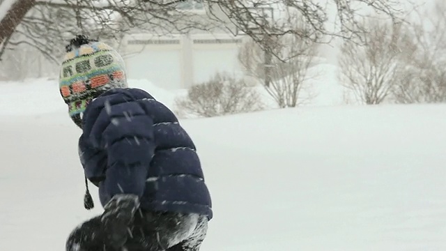 美国缅因州雅茅斯，一名男孩在暴风雪中在雪地里打滚嬉戏视频素材