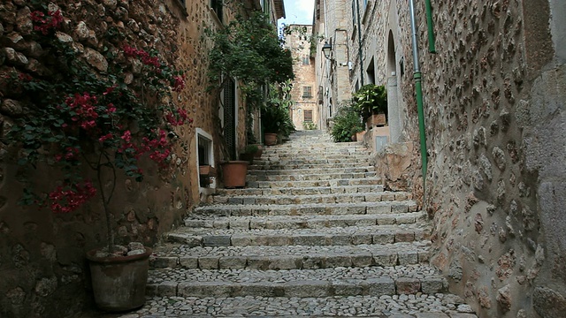 西班牙巴利阿里群岛Soller / Mallorca附近Fornalutx村的建筑之间排列着盆栽植物的石阶视频素材