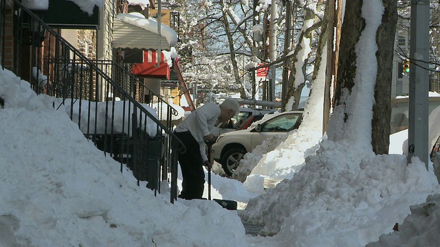 一位老人在人行道上铲雪/纽约，纽约，美国视频素材