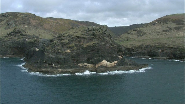 空中的岩石悬崖俯瞰海洋和周围起伏的绿色山丘/Boscastle，康沃尔，英国视频素材